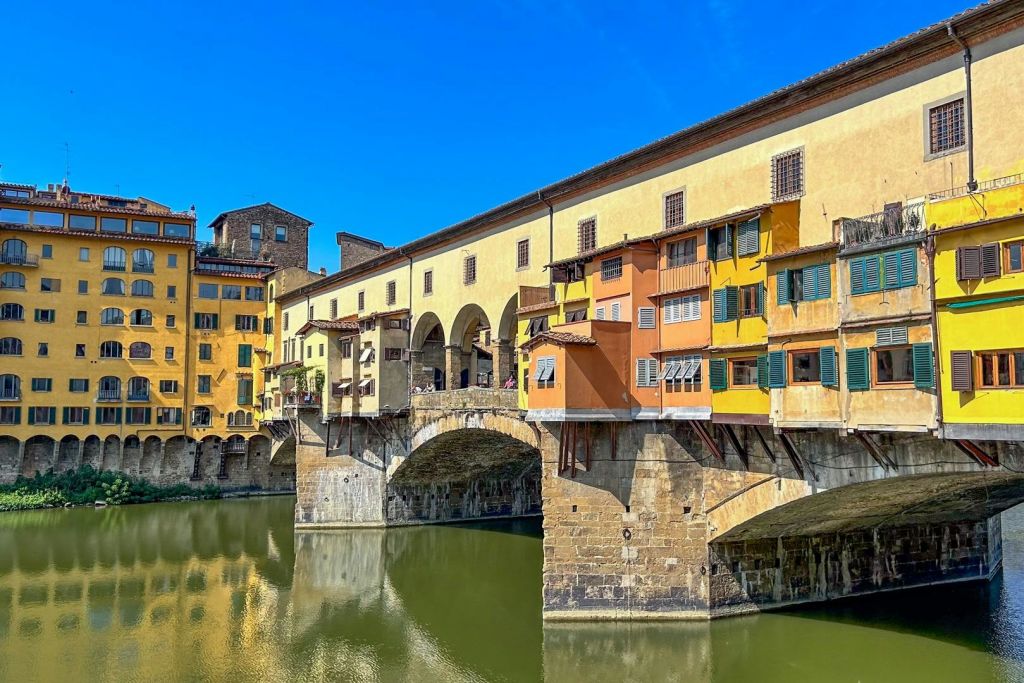 맑고 푸른 하늘 아래 강에 걸쳐 있는 화려한 건물이 있는 역사적인 다리입니다.