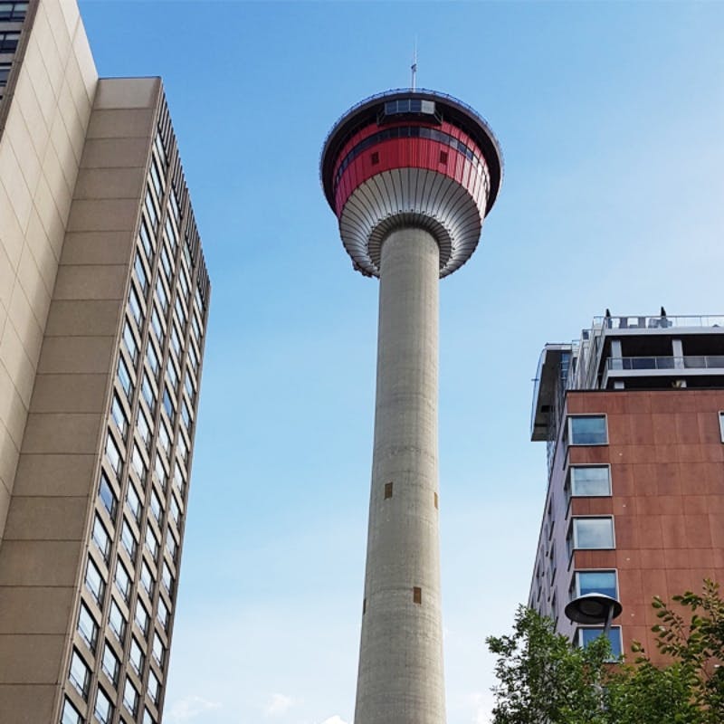 맑고 푸른 하늘 아래 두 개의 높은 건물 사이에 빨간색 전망대가 있는 콘크리트 전망대.
