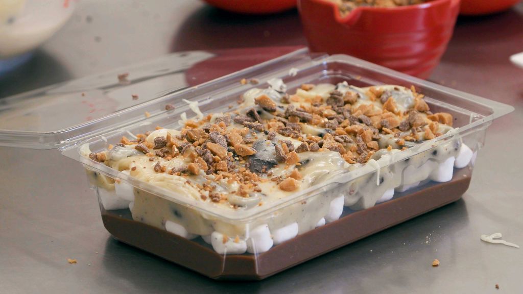 초콜릿, 마시멜로, 크림, 으깬 토피를 겹겹이 얹은 플라스틱 용기에 담긴 디저트.