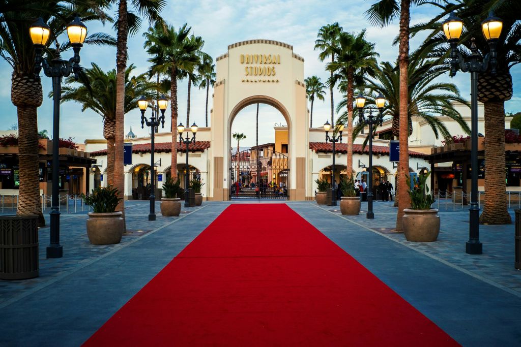 레드 카펫은 야자수와 장식 조명으로 둘러싸인 유니버설 스튜디오 할리우드 입구 아치로 이어집니다.