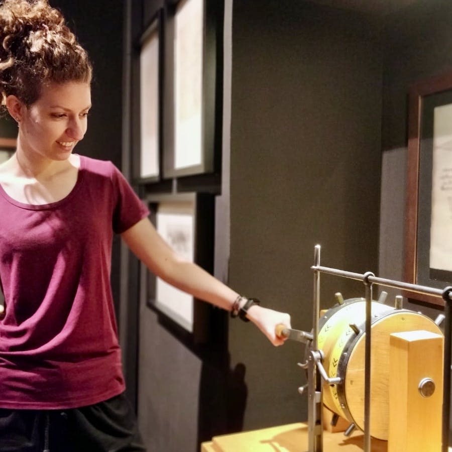 마룬 셔츠를 입은 사람이 박물관에서 기계 전시물과 상호 작용합니다.