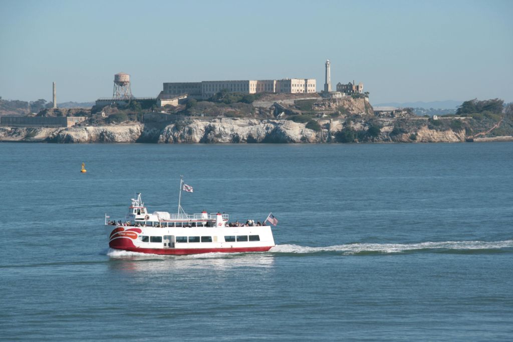 맑은 날 알카트라즈 섬과 건물을 배경으로 물 위에서 즐기는 페리보트.