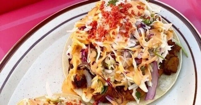 잘게 썬 채소, 소스, 깨진 토핑을 접시에 토핑한 타코를 클로즈업한 사진입니다.