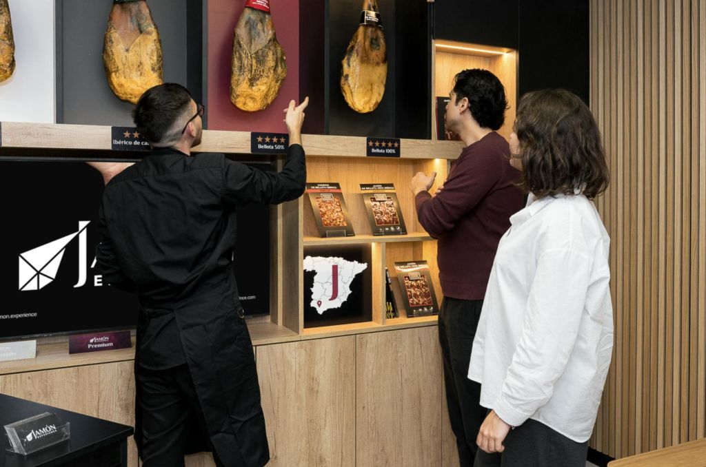 세 사람이 현대적인 매장에서 경화 햄과 정보 자료를 전시하고 있습니다.