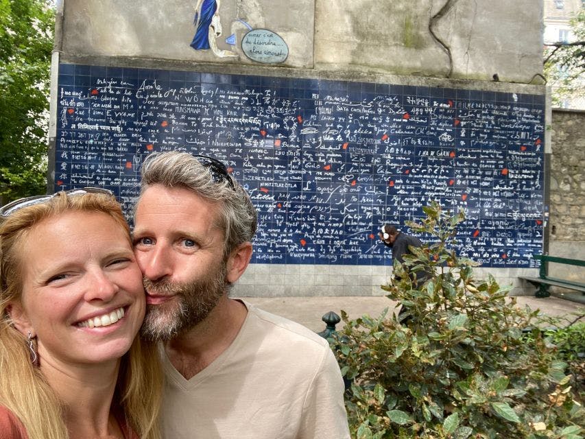 파리 몽마르트르의 다양한 언어로 장식된 '아이 러브 유 (I Love You)' 벽 앞에서 미소 짓는 부부가 포즈를 취하고 있다.