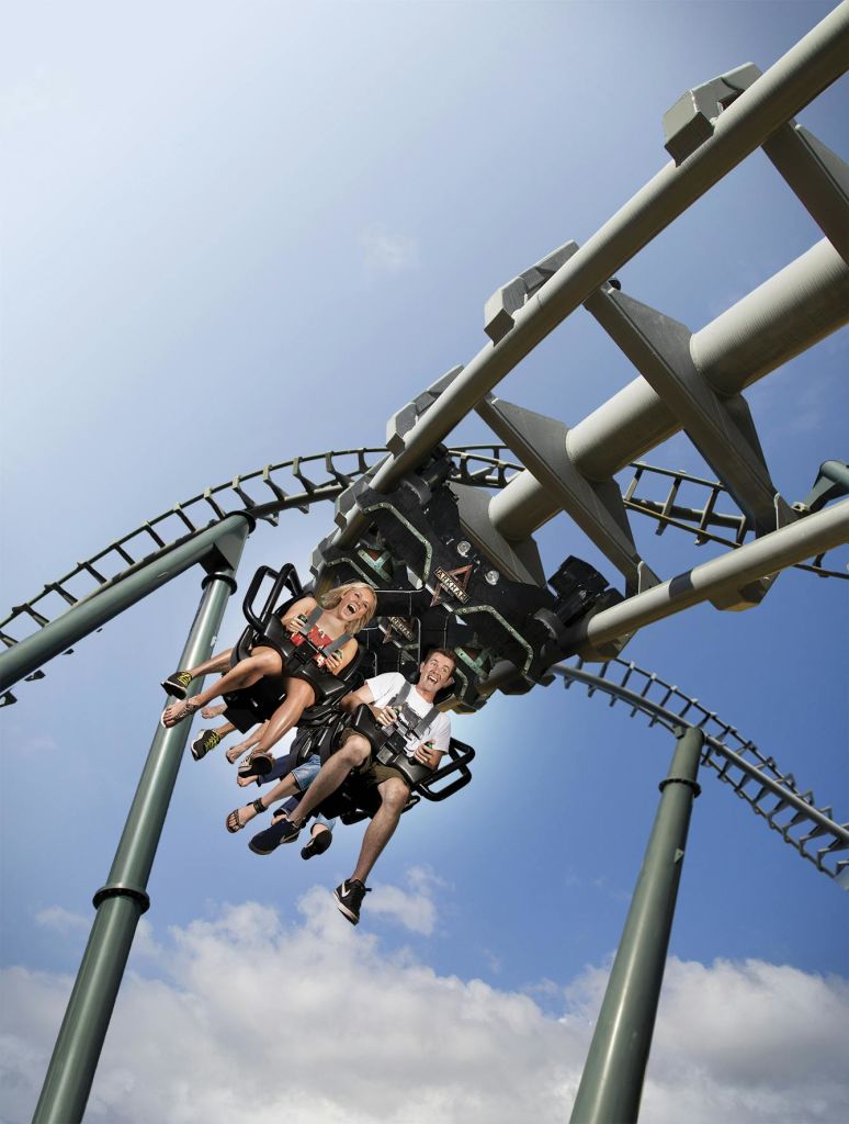 화창하고 푸른 하늘 아래 구름이 몇 개 있는 반전된 롤러코스터를 타고 있는 두 사람. 두 사람 모두 차량 서비스를 이용하고 있는 것으로 보입니다.