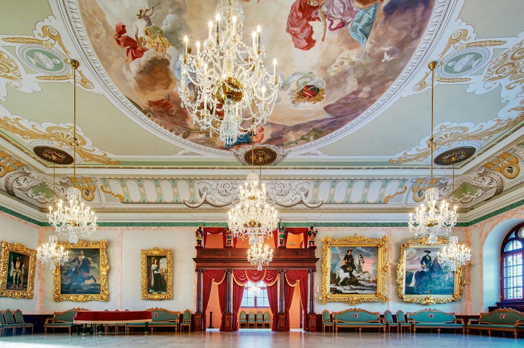 샹들리에, 커다란 그림, 붉은 드레이프 무대가 있는 화려한 연회장과 하늘을 형상화한 천장 벽화.
