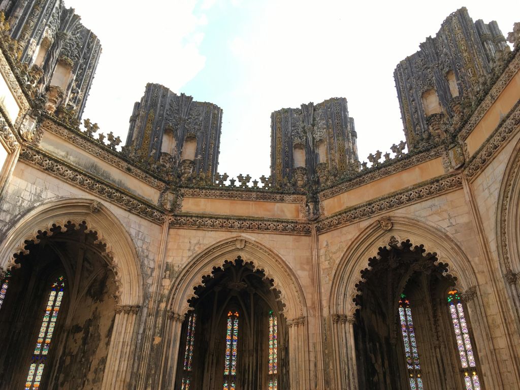 탁한 하늘 아래 스테인드글라스 창문이 있는 높고 화려한 타워와 아치가 있는 고딕 양식의 개방형 석조 구조물.