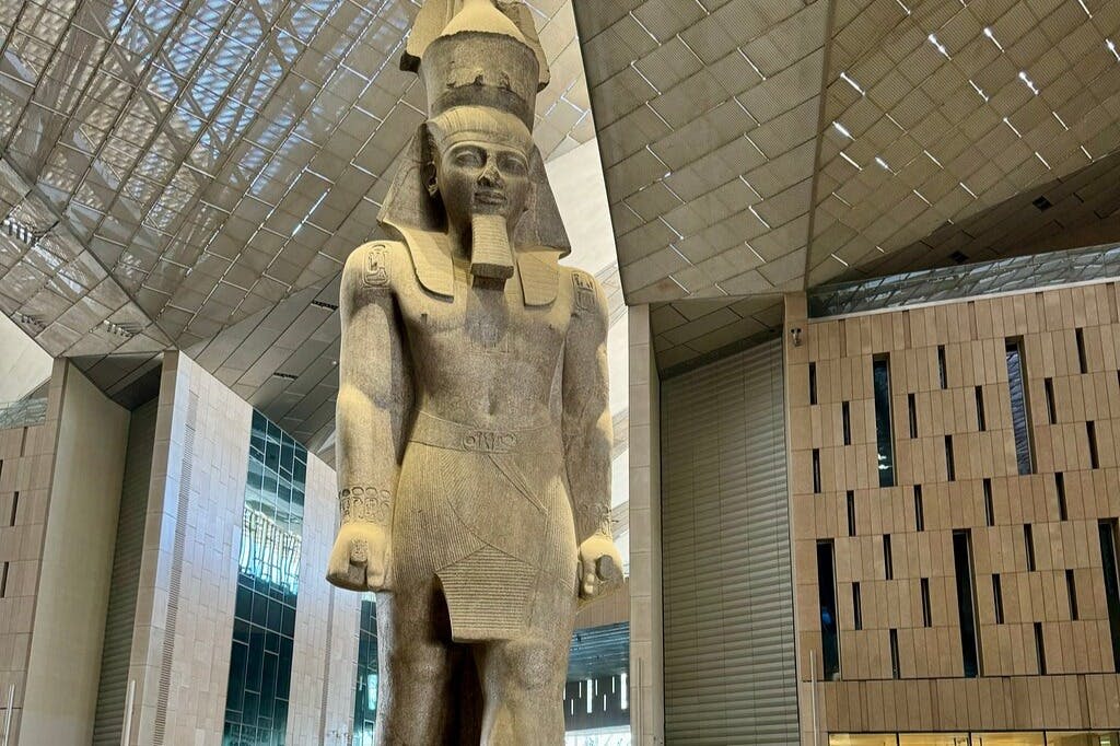 현대적인 실내 전시 공간에 전시된 머리 장식의 고대 이집트 인물의 대형 석상.