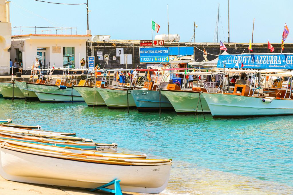 맑고 푸른 물과 하늘을 배경으로 다채로운 간판 광고 투어가 있는 부두에 정박한 작은 보트.