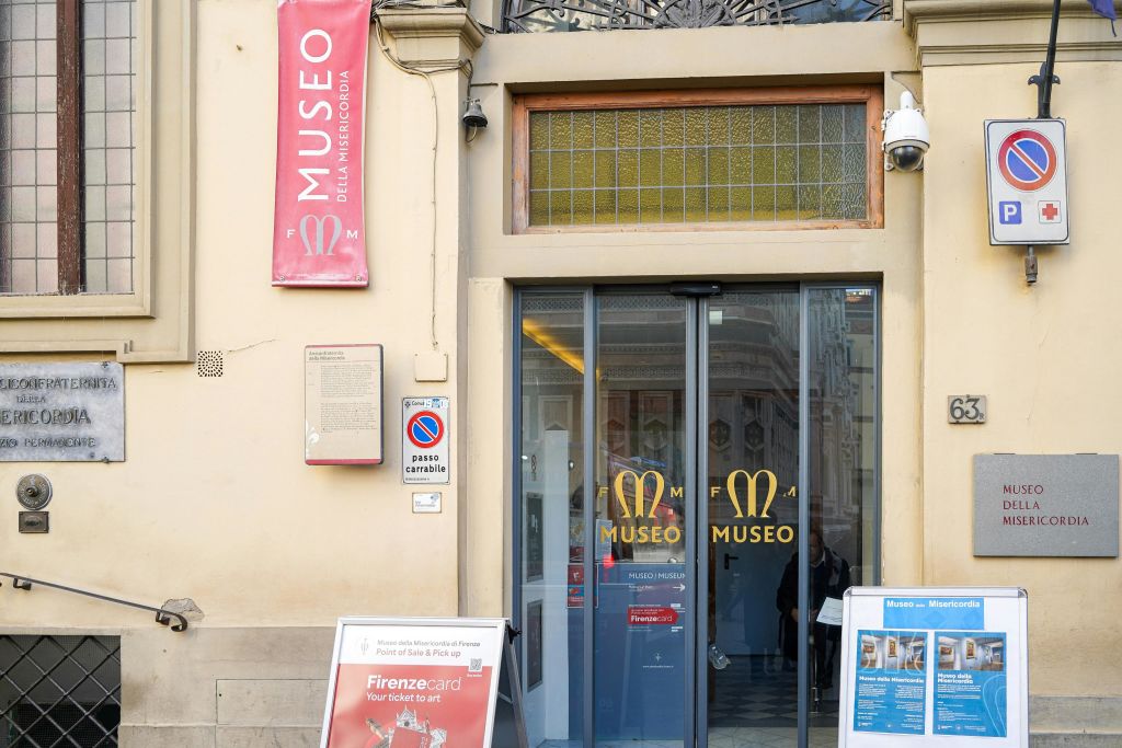 유리문, 간판, 외부의 정보 디스플레이가 있는 미세리코르디아 미술관 입구.