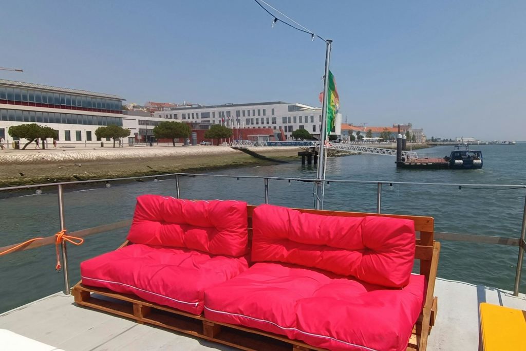 밝은 분홍색 쿠션 팔레트 2개는 아름다운 바닷가와 건물을 배경으로 도킹된 보트에 앉을 수 있습니다.