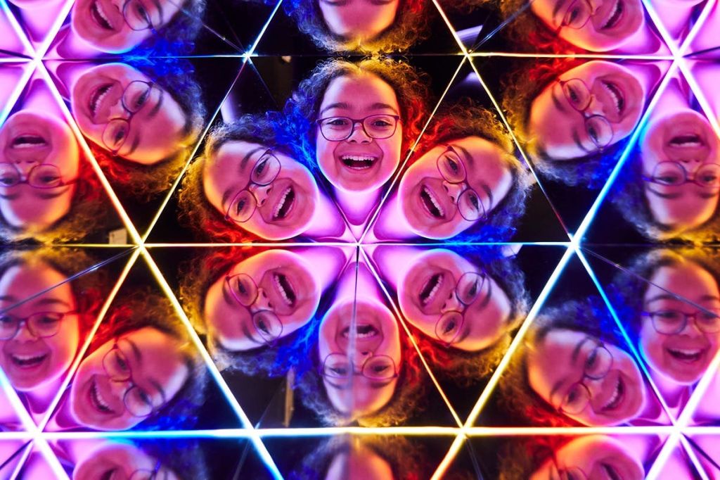 화려한 빛과 반사로 둘러싸인 안경과 곱슬머리를 가진 웃는 사람을 보여주는 만화경 효과.