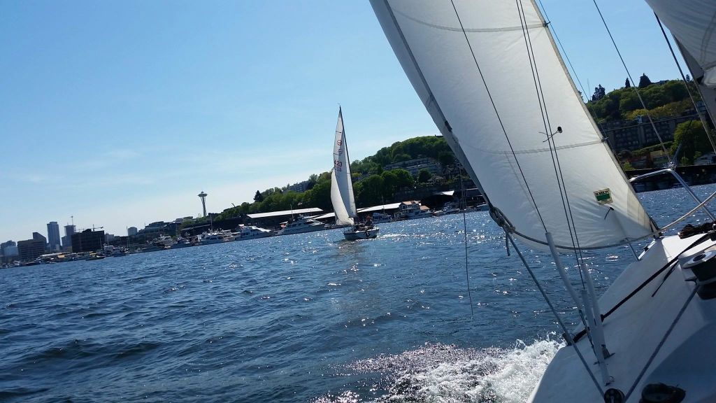 스페이스 니들을 배경으로 맑은 날의 요트와 잔잔한 물이 하늘을 반사합니다.