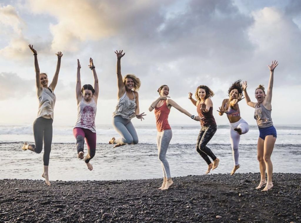 바다와 흐린 하늘을 배경으로 바위 해변에서 즐거운 미소를 짓고 있는 여섯 명의 여성.