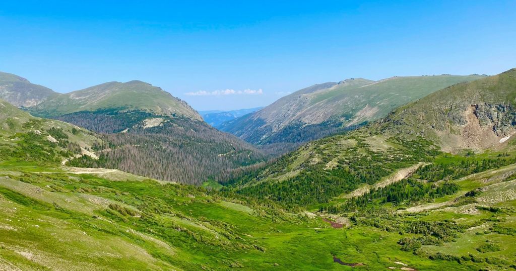 맑고 푸른 하늘 아래 산으로 둘러싸인 푸른 계곡의 경치.