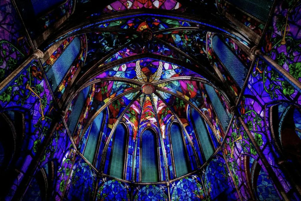 고딕 양식의 아치로 둘러싸인 정교하게 디자인된 스테인드 글라스 천장에는 생동감 넘치는 색상과 중앙의 골드 엔젤이 장식되어 있습니다.