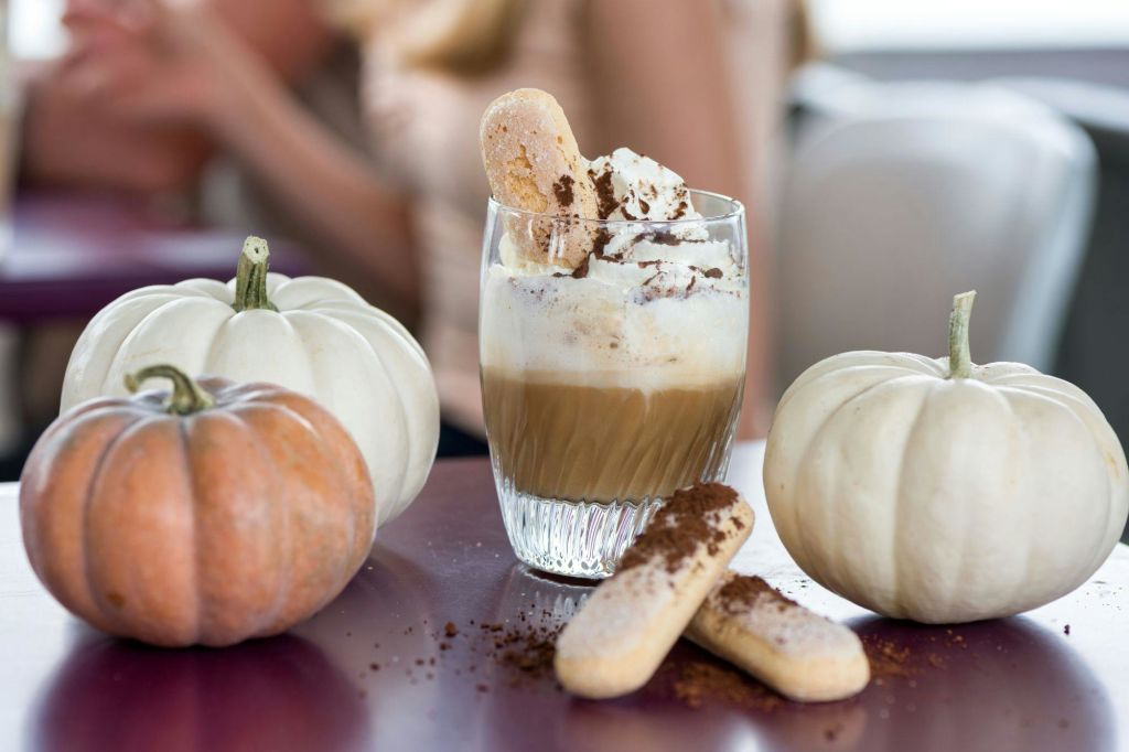 두 개의 흰 호박, 오렌지 호박, 비스킷으로 둘러싸인 휘핑 크림과 비스킷을 얹은 커피 한 잔.