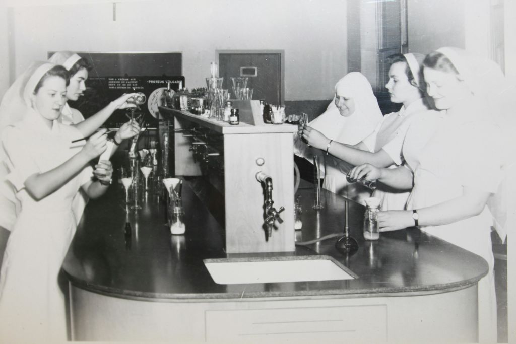 실험실에 있는 세 명의 간호사가 다양한 유리 제품을 취급하고 실험을 수행합니다.