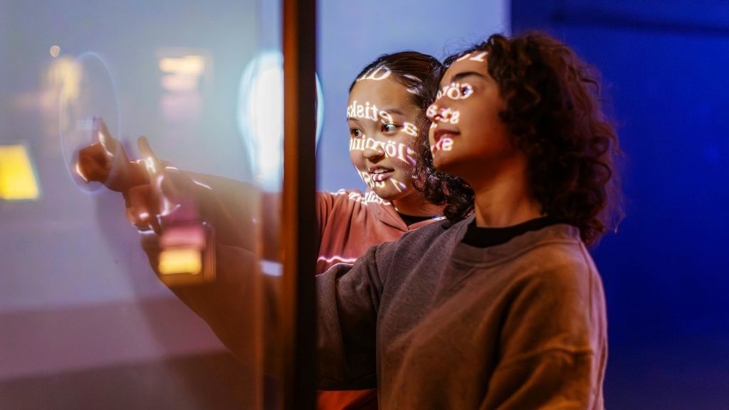 두 사람이 가까이 서서 화면을 바라보며 얼굴에 텍스트가 투영되어 있습니다.