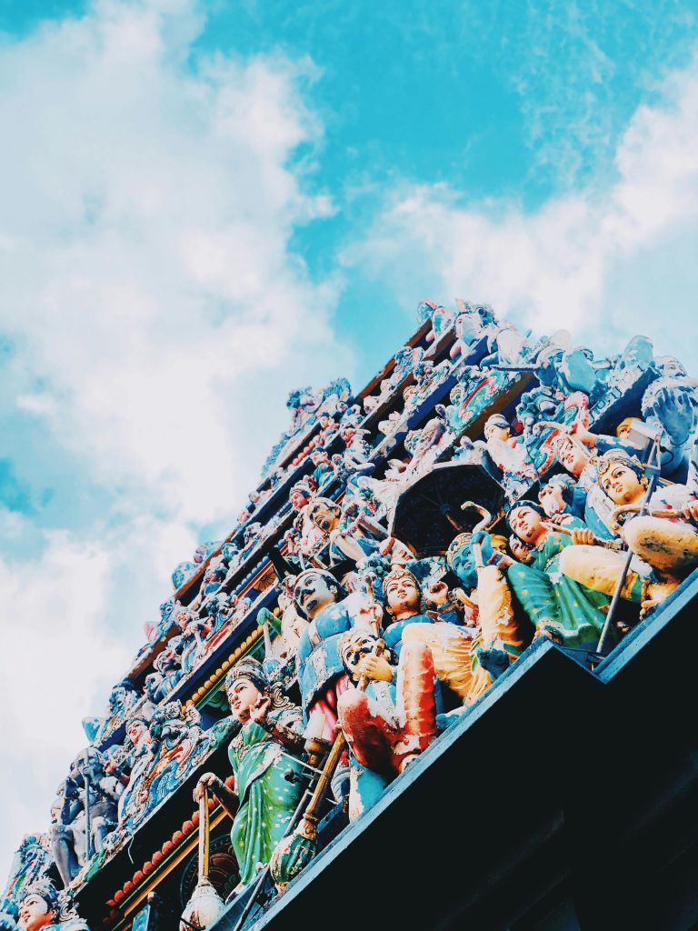 밝고 푸른 하늘 아래 수많은 케루빅 피규어로 가득한 사원 정면의 화려하고 정교한 부분.