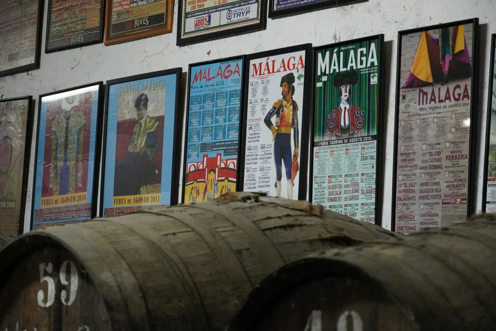 대형 나무 와인통 위의 벽에 말라가 투우 행사의 액자 포스터.
