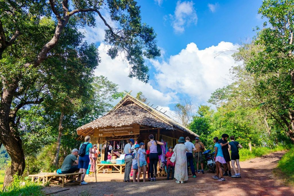 구름이 드리운 푸른 하늘 아래 나무들로 둘러싸인 초가지붕 오두막 앞에 한 무리의 사람들이 모여들었습니다.
