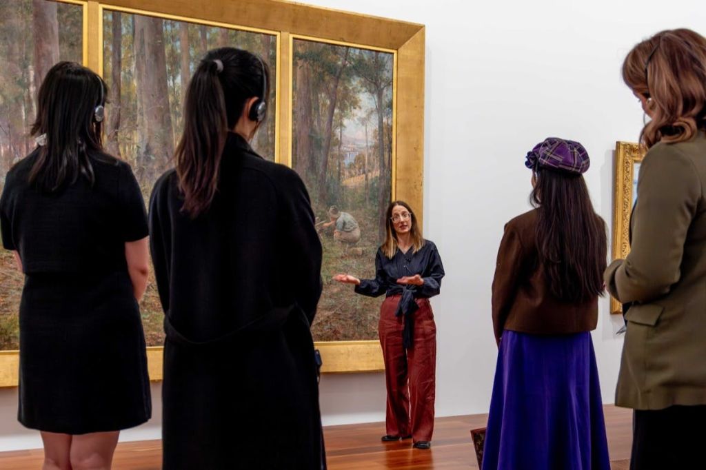 박물관의 액자에 담긴 그림 앞에서 갤러리 가이드가 관람객에게 말을 건넨다.