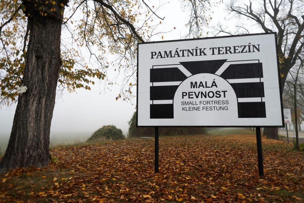 가을 낙엽과 맨 나무가 있는 안개가 자욱한 풍경에서 "Památník Terezín, Malá Pevnost (Small Fortress)" 에 서명하세요.