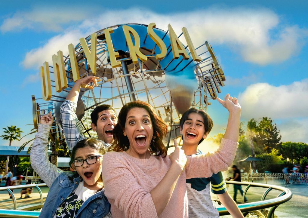 화창한 날 유니버설 스튜디오 지구의 랜드마크 앞에서 네 명의 가족이 신나게 포즈를 취하고 있습니다.