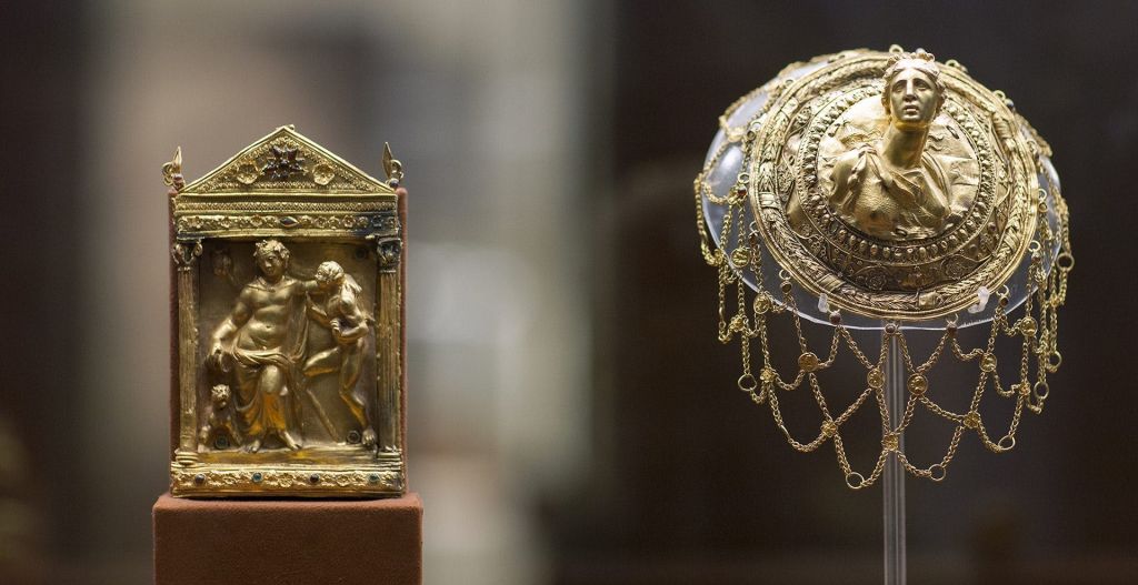 매달린 체인과 화려한 디테일로 장식된 인간 흉상의 중앙 부조가 있는 황금색의 정교하게 장식된 머리 장식.