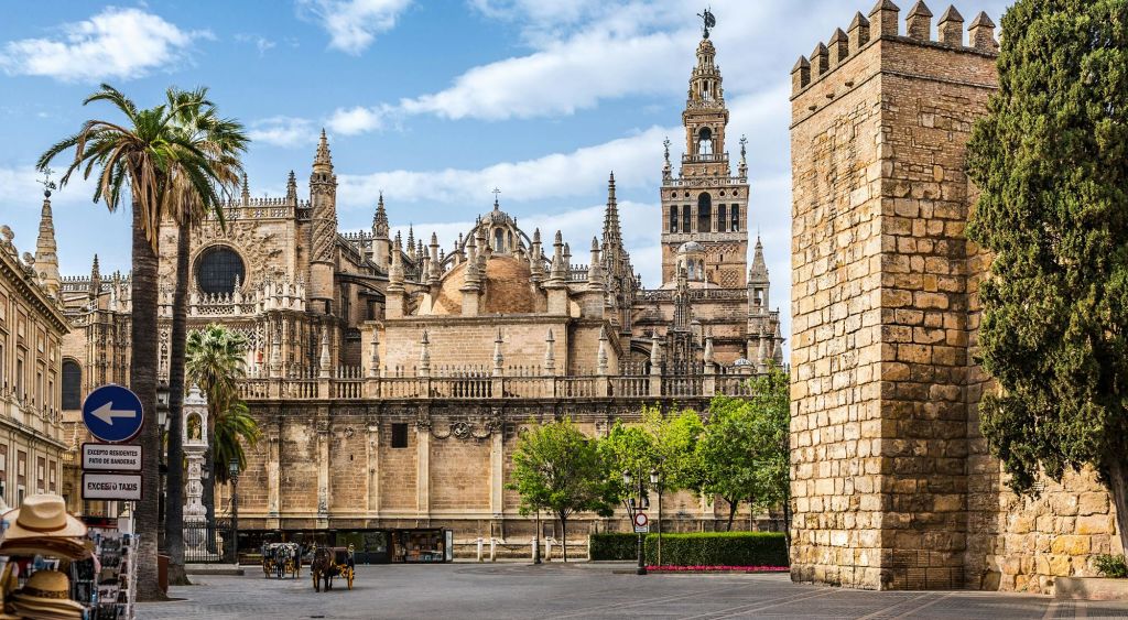 화려한 건축물과 첨탑, 높은 종탑이 있는 유서 깊은 대성당입니다. 나무와 말이 끄는 마차가 앞쪽에 있습니다.