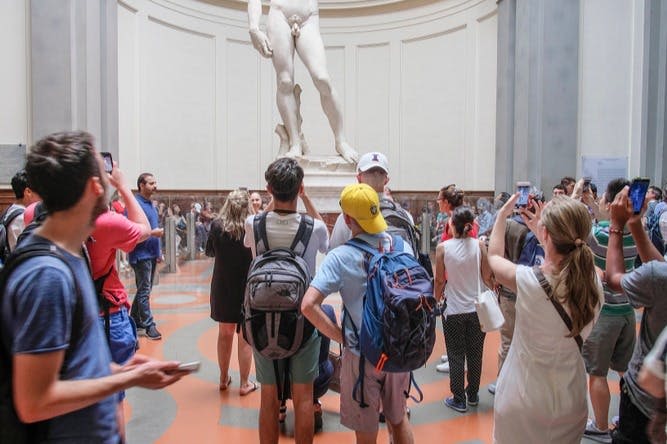 사람들은 피렌체를 돌아다니며 피렌체의 상징적인 조각상을 감상합니다.