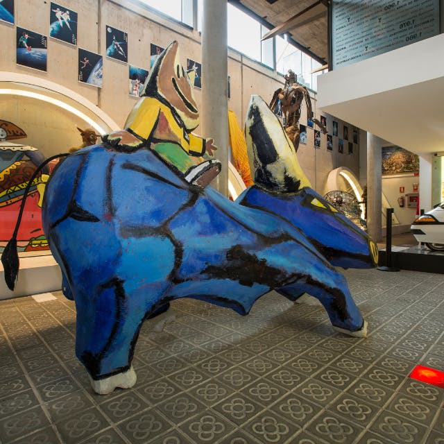 커다란 파란색 동물 모양의 조형물이 무늬가 있는 타일 바닥에 전시되어 있습니다.