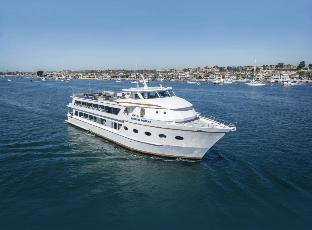 도시 경관과 정박지를 배경으로 잔잔한 푸른 바다를 항해하는 '엔들리스 드림스 (Endless Dreams)' 라는 이름의 대형 흰색 요트.