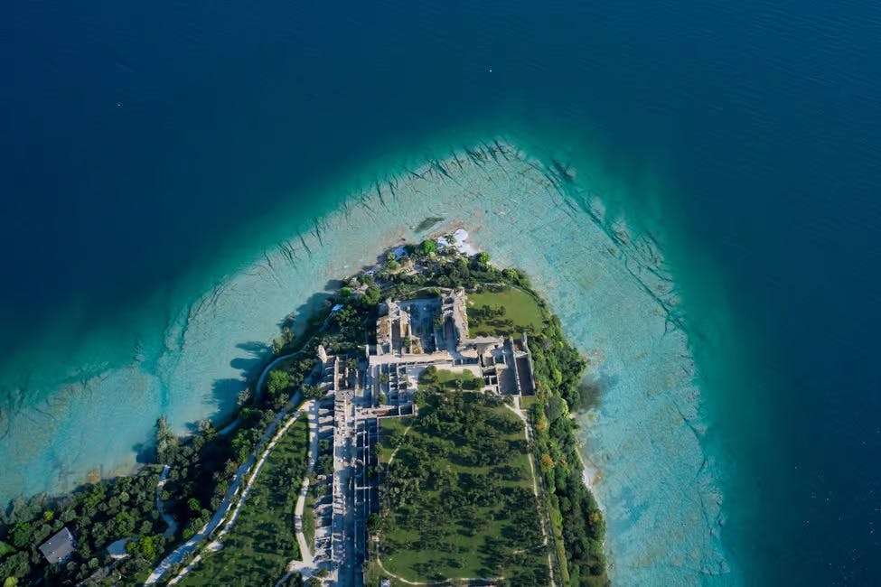 유적, 녹지, 주변의 청록색과 깊고 푸른 바다가 있는 섬의 공중 전망.