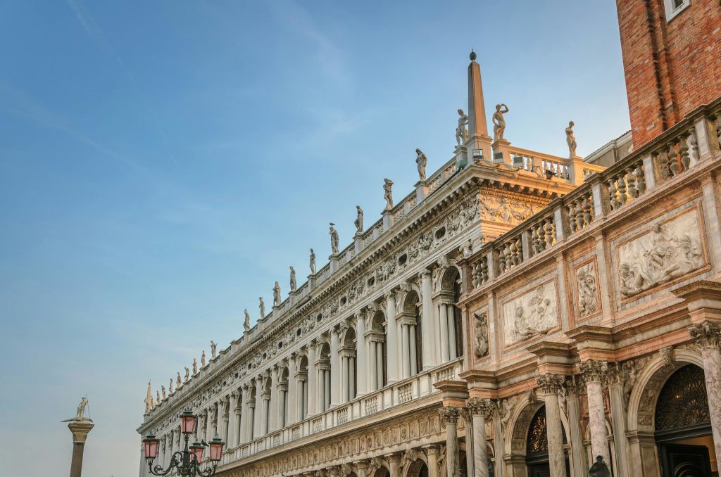 맑고 푸른 하늘 아래 기둥, 지붕의 조각품, 세밀한 조각품이 있는 화려하고 유서 깊은 건물.