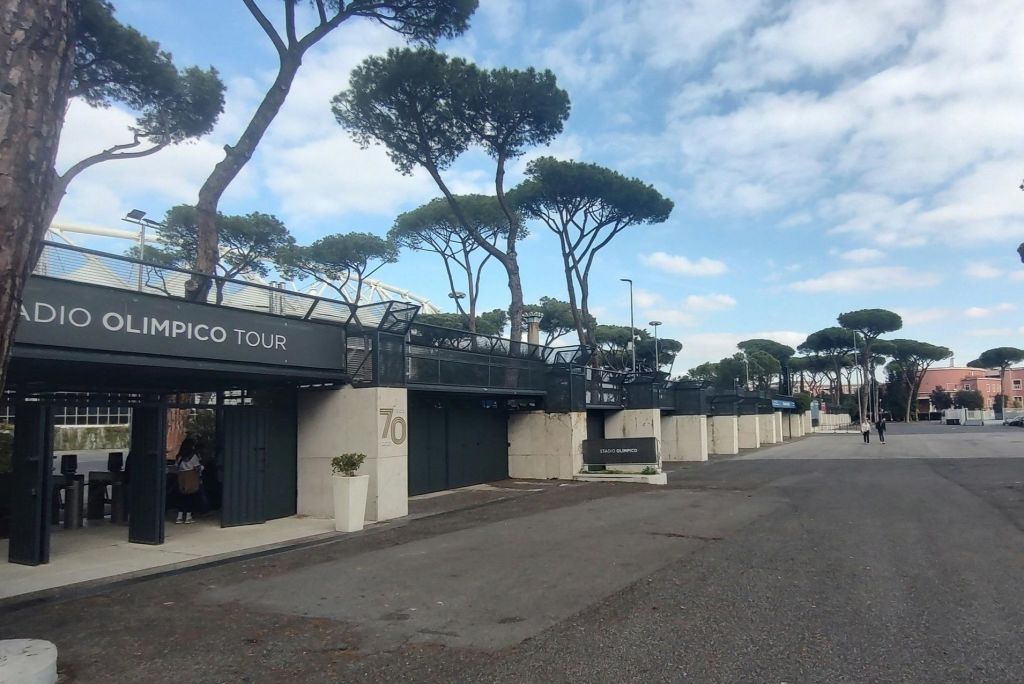 현대적인 건축물, 소나무, 맑은 하늘이 있는 투어 사이트 입구 공간.