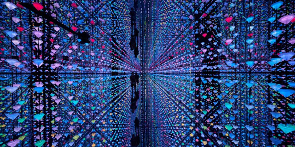 화려한 색상의 LED 조명이 달린 거울로 장식된 방은 만화경 효과를 내며, 사람들의 실루엣이 보입니다.