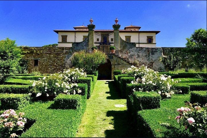 석조 계단, 잘 다듬어진 울타리, 맑고 푸른 하늘 아래 하얀 장미가 피어 있는 유서 깊은 저택입니다.