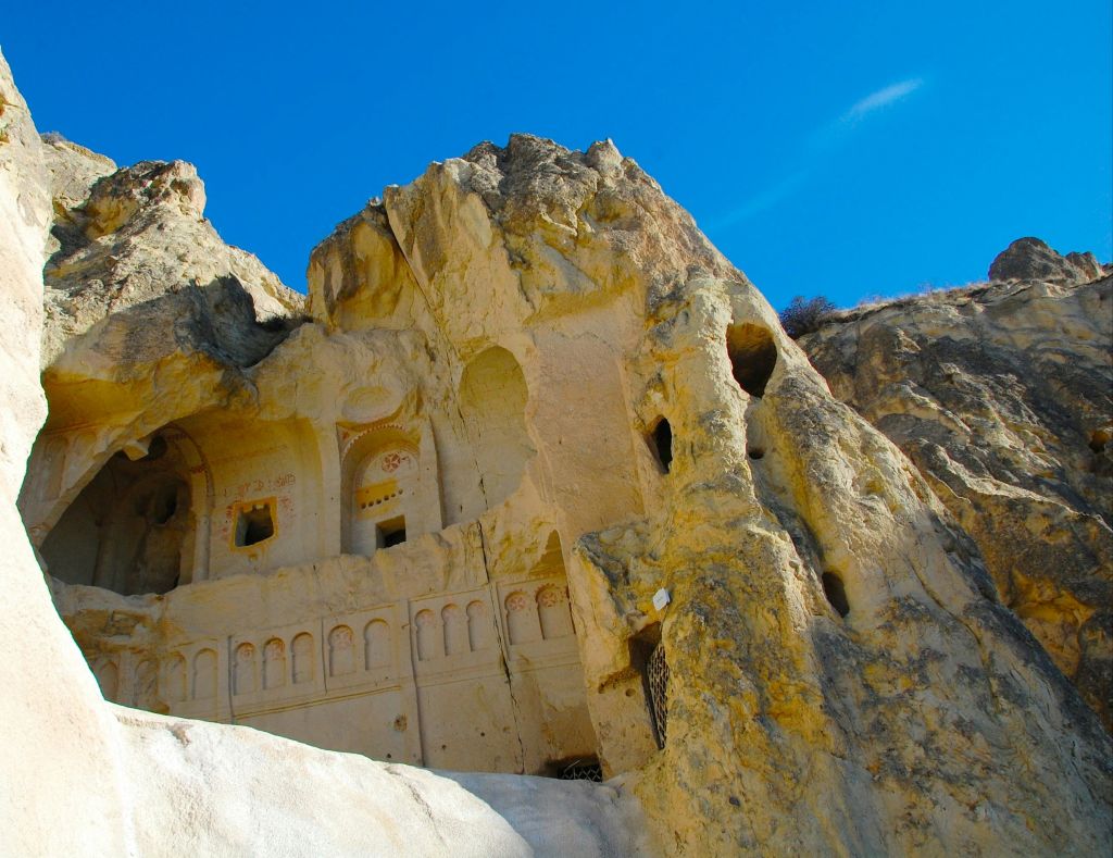 맑고 푸른 하늘 아래 바위 절벽에 조각된 고대의 바위 컷 건축물.