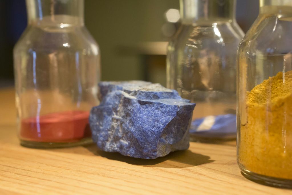 세 개의 투명한 유리병으로 둘러싸인 나무 표면에 놓인 거친 푸른 돌.