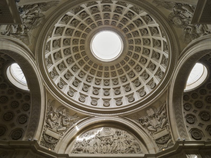 중앙 오큘러스가 있는 화려한 돔 천장, 정교한 조각, 클래식한 스타일로 다양한 인물을 묘사한 디테일한 부조.