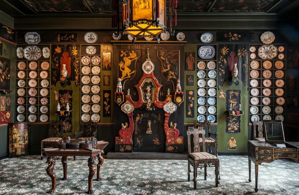 장식용 벽 접시, 짙은 목재 가구, 무늬가 있는 카펫, 용과 꽃을 모티브로 한 정교한 벽 예술품이 있는 화려한 객실.