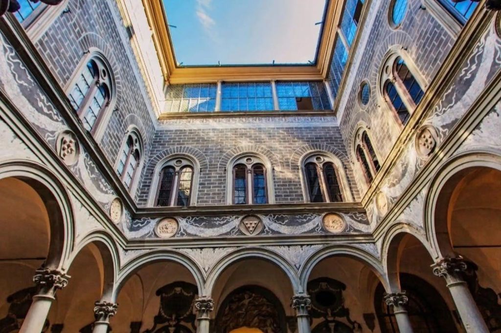 아치형 창문, 정교한 석조물, 푸른 하늘의 탁 트인 전망을 자랑하는 유서 깊은 건물의 내부 안뜰.