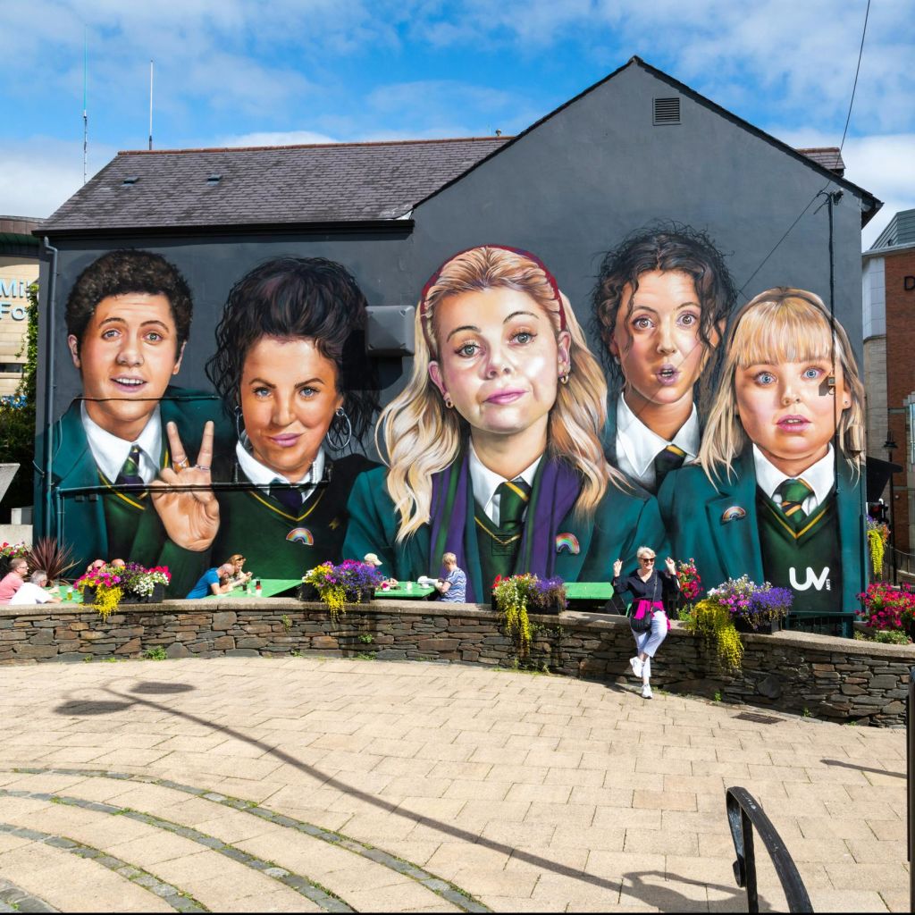 건물 한켠에 교복을 입은 다섯 사람이 꽃을 들고 앞에 앉아 있는 모습을 형형색색의 벽화로 표현했습니다.