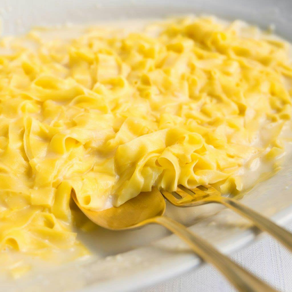 황금 포크 두 개를 곁들인 크리미 페투치네 파스타 한 접시.