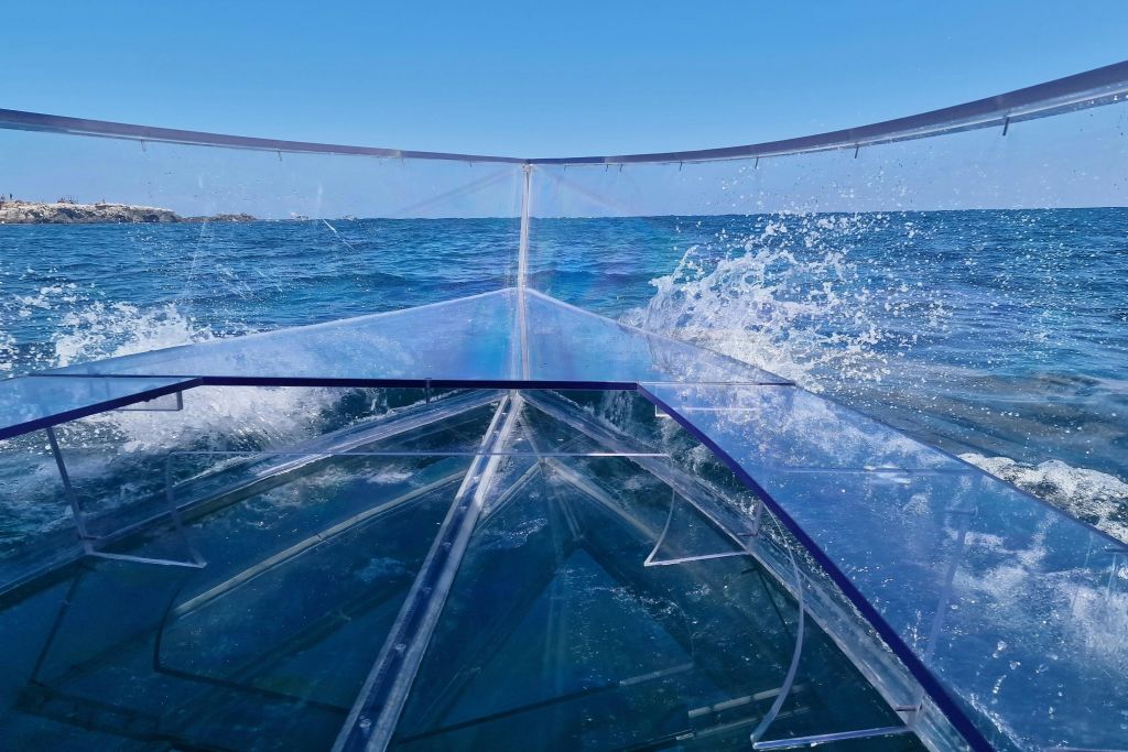 맑고 푸른 물 위에 파도가 치는 투명한 보트, 푸른 하늘 아래.