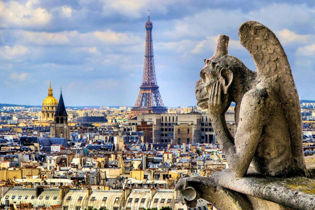 부분적으로 흐린 하늘 아래 배경으로 에펠탑이 눈에 띄게 떠오르는 파리를 내려다보는 석조 가고일.