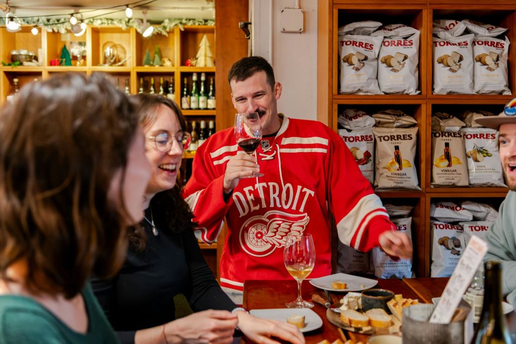 병 선반을 배경으로 아늑한 분위기에서 테이블에서 음료를 마시며 대화를 나누는 세 사람.